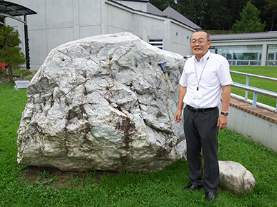 写真4–a：ミュージアム館外に展示されているヒスイの巨礫と学芸員の竹之内博士