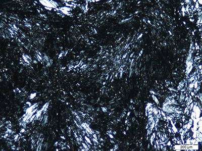 図７b：青海産ラベンダーヒスイ中に見られる放射状構造を示す細少なヒスイ集合体ー交差偏光写真