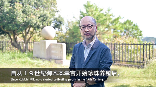 写真2. 発表者の中村雄一氏、真円真珠発明者頌徳碑の前で(本人の許諾を得て掲載しています)